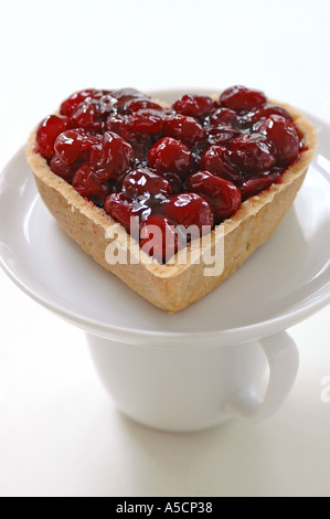 A forma di cuore crostata di ciliegia sul piattino bilanciamento sulla tazza Foto Stock