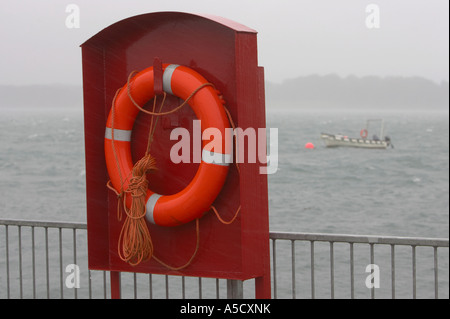 Lifebelt con la guida sotto la pioggia con una piccola barca da pesca ormeggiate in background su un giorno di tempesta Portaferry contea di Down Foto Stock