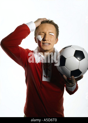 Giovane uomo con la bandiera della Polonia dipinto sul volto tenendo palla calcio a occhi chiusi Foto Stock