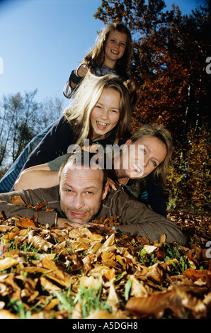 Familiy giacente su foglie di autunno Foto Stock