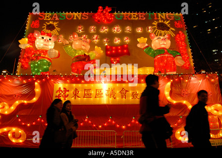 I pedoni a piedi passato strada illuminata decorazioni per "anno del maiale' Anno Nuovo Cinese di Hong Kong, Cina. Foto Stock