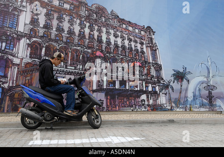 Giovane uomo cinese ubicazione su uno scooter e utilizzando il suo telefono cellulare in Macao Cina Foto Stock