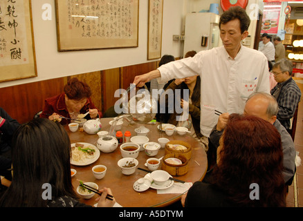 Cameriere versando il tè in un tradizionale tè cinese-house e la penisola di Kowloon. Hong Kong Cina Foto Stock