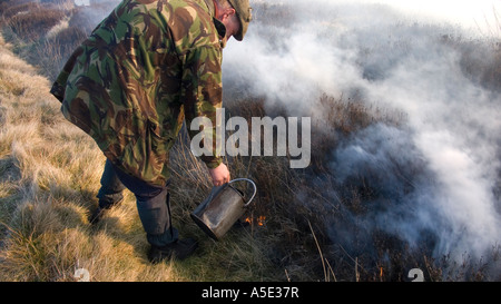 Guardiacaccia spegnimento incendio durante la controllata heather burning sulla North Yorkshire Moors, Regno Unito Foto Stock