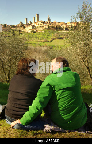 San Gimignano Toscana ItalyCouple avente un picnic in un oliveto con la vista delle tante torri verticali Foto Stock