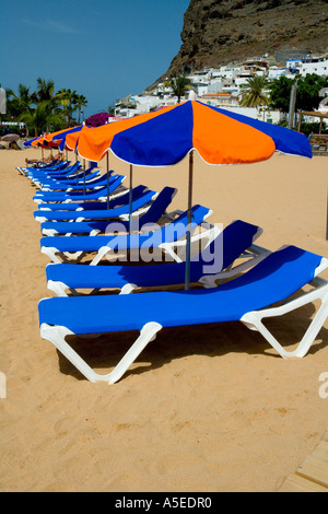 Blu e arancione di ombrelloni e lettini sulla spiaggia di Puerto de Mogan, Gran Canaria, Isole Canarie, Spagna. Foto Stock