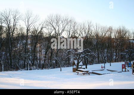 Parco giochi invernale: Una spolverata di neve su un parco silenzioso al crepuscolo. Foto Stock