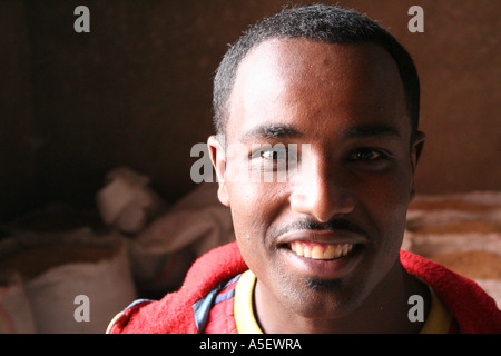 Attraente sorridente giovane uomo nero in un grano macinando la fabbrica, Harar, Etiopia Foto Stock