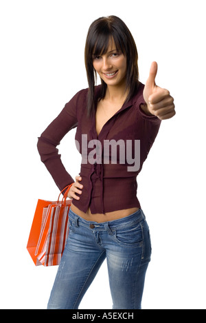 Giovane donna in piedi con lo shopping di sacchetti di carta e mostra OK dal canto isolato su bianco in studio Foto Stock