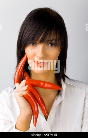 Donna con peperoni rossi sulle sue dita sfondo bianco in studio Foto Stock