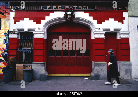 Uomo con scarpe da ginnastica e un cappello che passa davanti alla facciata della Fire Patrol Number 2 Fire Station di New York USA Foto Stock