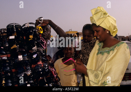 Donna in abiti tradizionali shopping per occhiali da sole dal mercato in stallo, Nouakchott, Mauritania, Africa Foto Stock