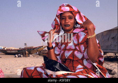 Donna della Mauritania in colorate abbigliamento tradizionale seduta sulla spiaggia, Nouakchott, Mauritania, Africa Foto Stock