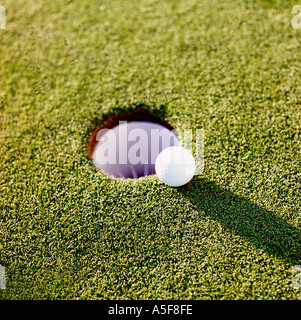 Pallina da golf che rotola vicino alla tazza. Foto Stock