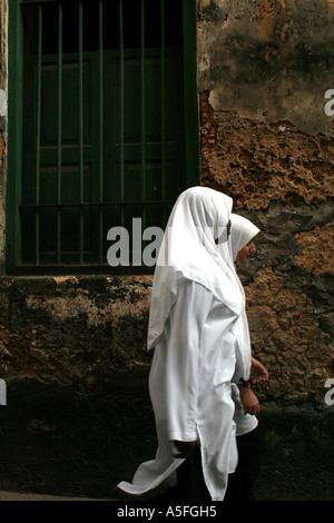 Due ragazze a piedi attraverso le strette strade di Stonetown, Zanzibar, Tanzania Foto Stock