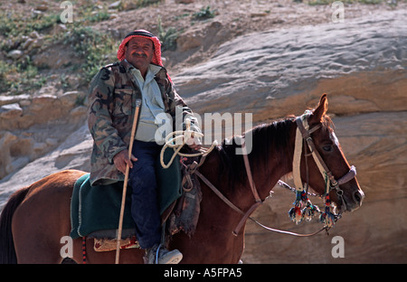 Beduina locale gli abitanti di un villaggio di Offerta equitazione dall ingresso del Siq di Petra, indossando una keffiyah Giordania Medio Oriente Foto Stock