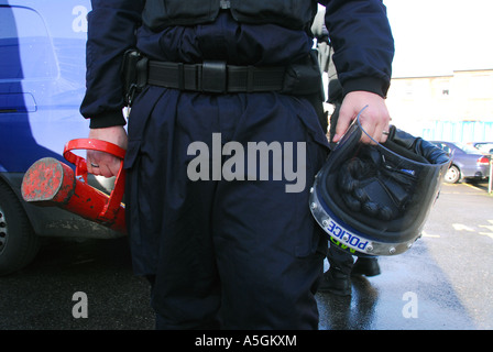 Funzionario di polizia che porta casco e ariete in preparazione per il raid su cocaina crack house nella zona ovest di Londra Foto Stock