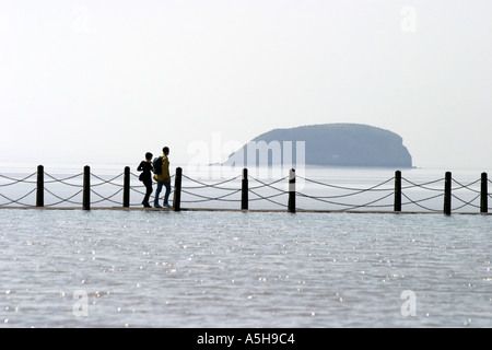 Coppie giovani a piedi lungo la passeggiata del lago marino in Weston super Mare e sale fino al centro Foto Stock