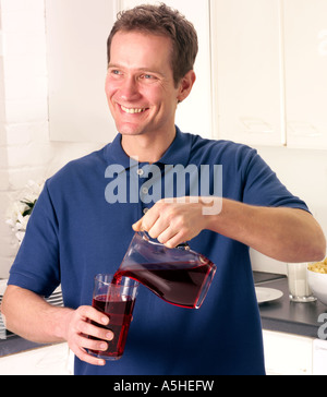 Uomo in cucina con il succo di mirtillo palustre Foto Stock