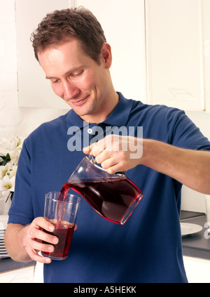 Uomo in cucina con il succo di mirtillo palustre Foto Stock