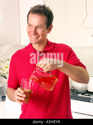 Uomo in cucina versando il succo di mela Foto Stock