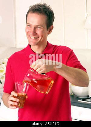 Uomo in cucina versando il succo di mela Foto Stock