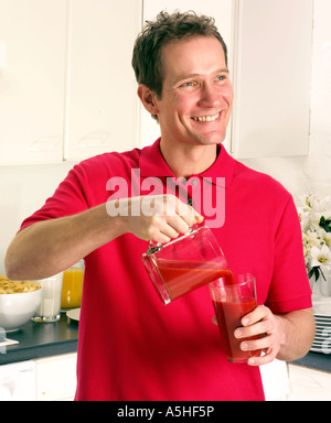 Uomo in cucina versare il succo di pomodoro Foto Stock