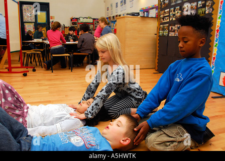 Alunni di una scuola primaria a Kingston, West London, impegnarsi nella meditazione e massaggio della testa, UK. Foto Stock