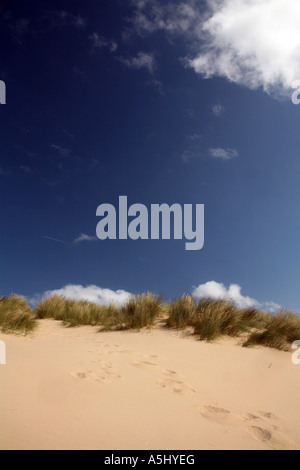 Piedi stampe in dune di sabbia contro un cielo blu Foto Stock