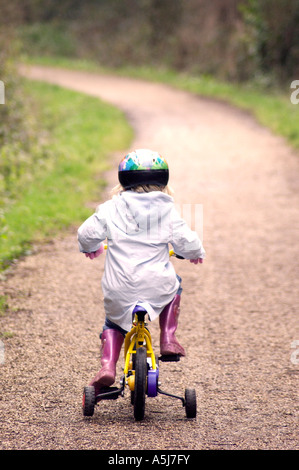 Bambino britannico escursioni in bicicletta con stabilizzanti in London Park Regno Unito Foto Stock