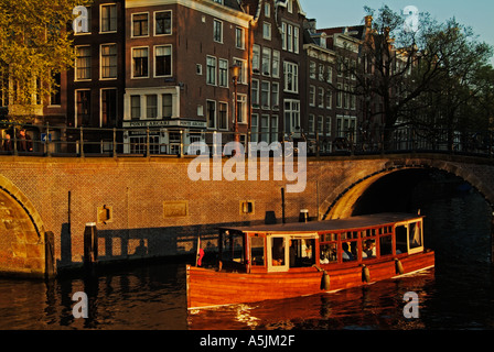 In vecchio stile in legno piccolo canal tour in barca di crociera su una crociera serale sui canali di Amsterdam Paesi Bassi Olanda UE Europa Foto Stock