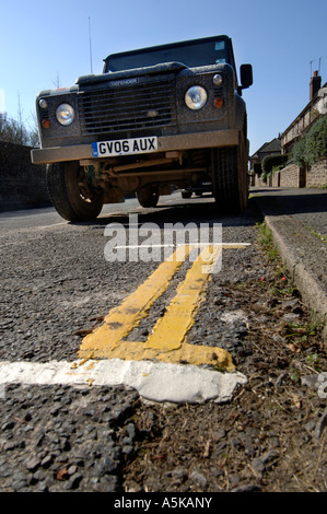 Un Land Rover Defender accanto a un periodo molto breve a doppia linea gialla su una strada in Falmer East Sussex Foto Stock