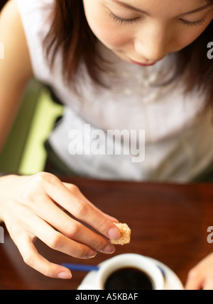 Giovane donna aggiungendo lo zucchero nel tè Foto Stock