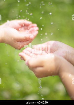 Due coppie di mani la cattura di gocce di acqua Foto Stock