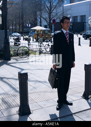 Uomo asiatico in attesa di attraversare la strada Foto Stock