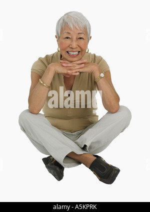 Studio shot di senior donna seduta zampe trasversale Foto Stock