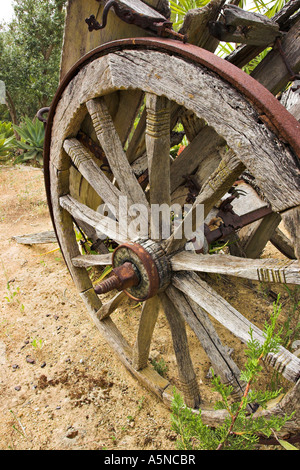 Abbandonato il carrello ruota: l'acciaio stanchi stanchi della ruota motrice di un vecchio weathered due ruote carrello di bue o carro impostato in un deserto-come lo spazio Foto Stock