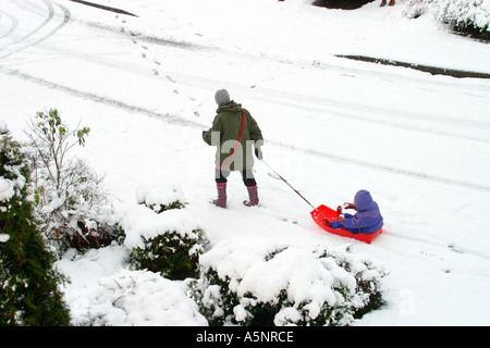 Madre tirando il toddler in slitta Foto Stock