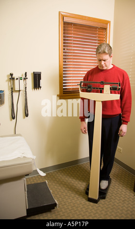 Uomo del peso di se stesso nel medico della sala d'esame. Foto Stock