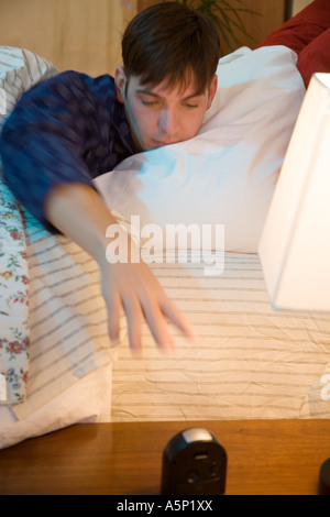 Giovane uomo raggiunge per la sua radiosveglia per vedere che cosa ora è. Non riesco a dormire. Foto Stock