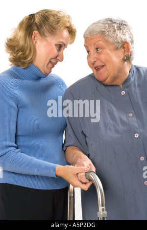 Cura donna usando un walker colloqui con il suo terapista fisico o la figlia o un amico. Foto Stock