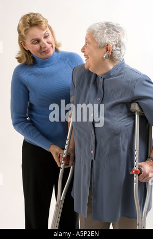 Figlia, amico o home healthcare lavoratore visite/assiste donna anziana con le stampelle. Foto Stock