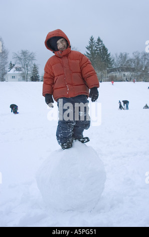 Signor sei anno vecchio ragazzo permanente sulla grande palla di neve Foto Stock