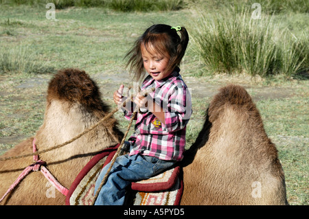 Giovane ragazza mongolo è seduto tra le due gobbe di cammello Bactrian Mongolia Foto Stock