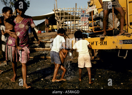 MOUNT PINATUBO DISASTER FEBBRAIO 1991 un giovane bambino viene lavata mediante i figli grandi come acqua fresca è consegnato al camp Foto Stock