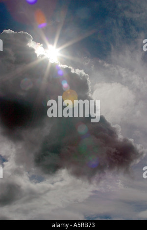 Moody sky con Sun che emergono da dietro dark cloud Foto Stock