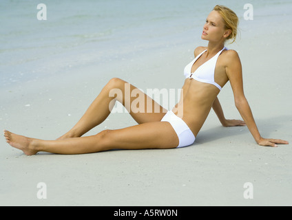 Donna in bikini seduto sulla spiaggia Foto Stock