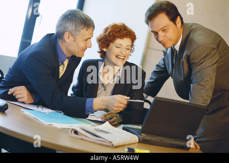 Colleghi di lavoro utilizzando laptop, ridendo Foto Stock