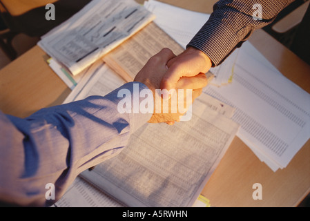 Imprenditori agitando mani su tavola, vista ritagliata, pagine finanziarie dei quotidiani in background Foto Stock