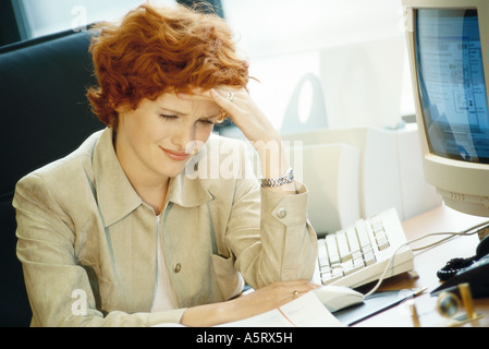 Imprenditrice seduto alla scrivania, tenendo la testa Foto Stock